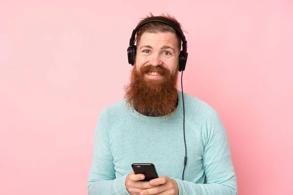 Homem Ruivo Com Barba Longa Sobre Fundo Rosa Isolado Ouvindo — Fotografia de Stock