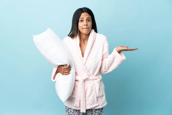 Young woman in pajamas over isolated background in pajamas and making doubts gesture while lifting the shoulders