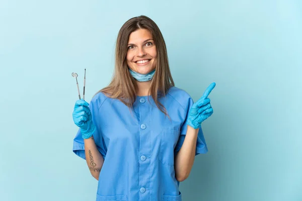 Eslovaca Dentista Segurando Ferramentas Isoladas Fundo Azul Apontando Para Lado — Fotografia de Stock