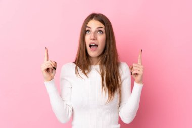 Soyutlanmış pembe arka planı olan genç bir kadın şaşırmış ve yukarı bakıyor.