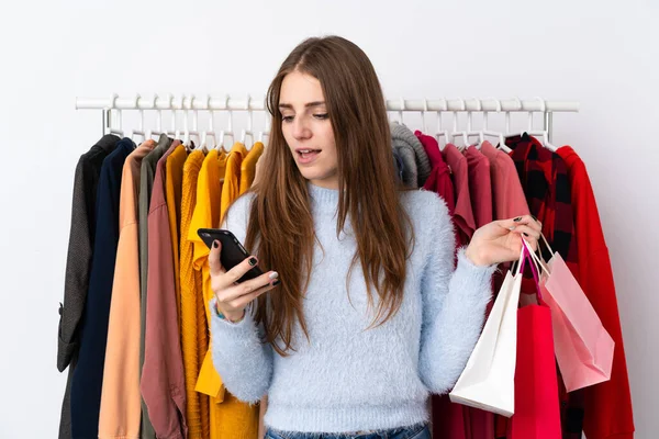 Young woman in a clothing store with a mobile