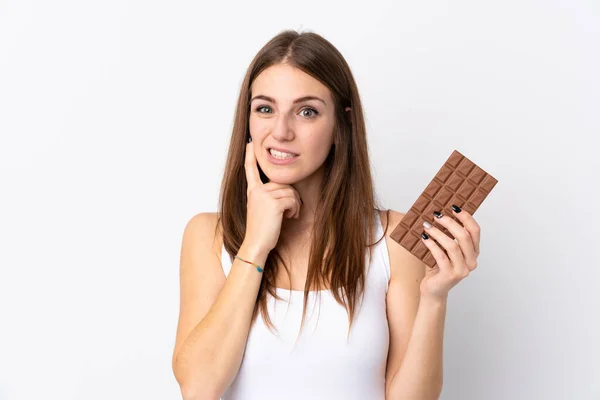 Mladá Žena Izolovaném Bílém Pozadí Čokoládovou Tabletu Mají Pochybnosti — Stock fotografie