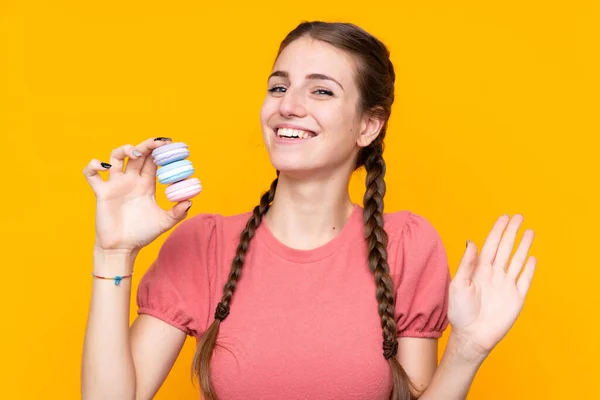 Giovane Donna Sfondo Giallo Isolato Con Macaron Francesi Colorati Saluti — Foto Stock