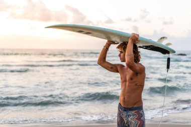 Kafkasyalı genç adam gün doğumunda sörf yapmak için erken kalkar.