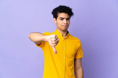 Genç Venezuelalı bir adam mor arka planda izole edilmiş.