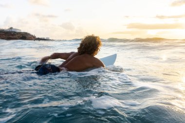 Kafkasyalı genç adam gün doğumunda sörf yapmak için erken kalkar.