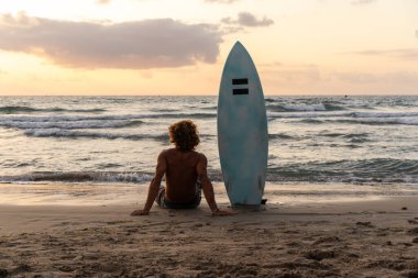 Kafkasyalı genç adam gün doğumunda sörf yapmak için erken kalkar.