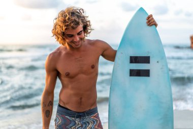 Kafkasyalı genç adam gün doğumunda sörf yapmak için erken kalkar.