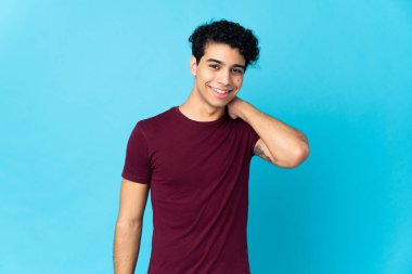 Genç Venezuelalı adam mavi arka planda izole edilmiş gülüyor.