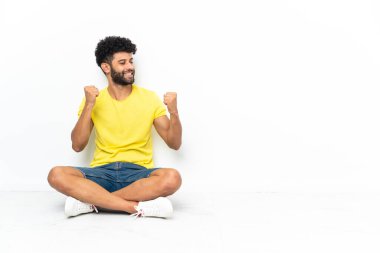 Genç Faslı yakışıklı adam tecrit edilmiş arka planda oturmuş zaferi kutluyor.