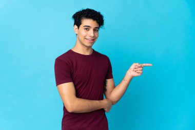 Genç Venezuelalı bir adam mavi arka planda izole edilmiş.