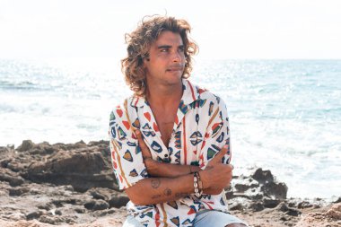 Sahilde kafası karışmış genç bir adam.