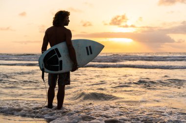 Kafkasyalı genç adam gün doğumunda sörf yapmak için erken kalkar.