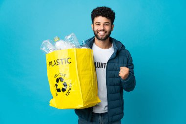 Genç Fas 'lı elinde plastik şişelerle dolu bir çantayla izole arka planda zaferi kutluyor.