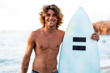 Kafkasyalı genç adam gün doğumunda sörf yapmak için erken kalkar.