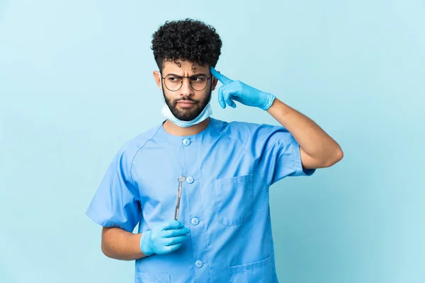 Homem Dentista Marroquino Segurando Ferramentas Isoladas Fundo Azul Com Dúvidas — Fotografia de Stock