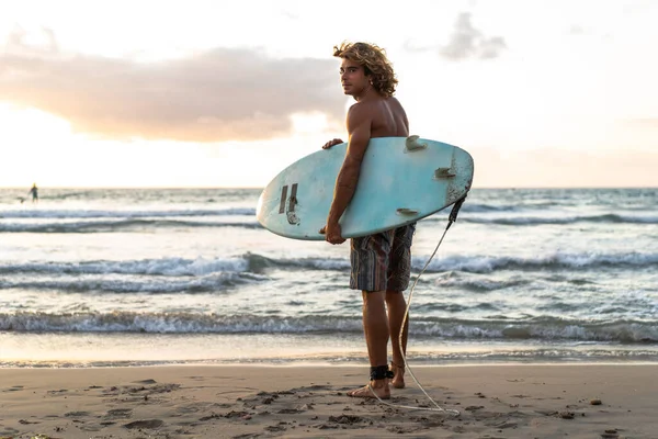 Kafkasyalı genç adam gün doğumunda sörf yapmak için erken kalkar.