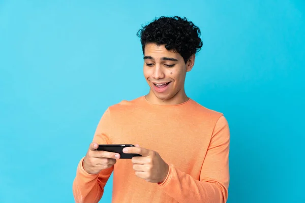 Venezuelan Man Isolated Blue Background Playing Mobile Phone — Stock Photo, Image