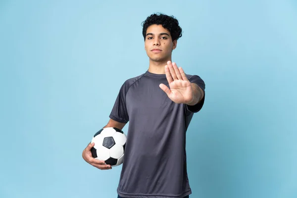 Venezuelan football player man over isolated background making stop gesture