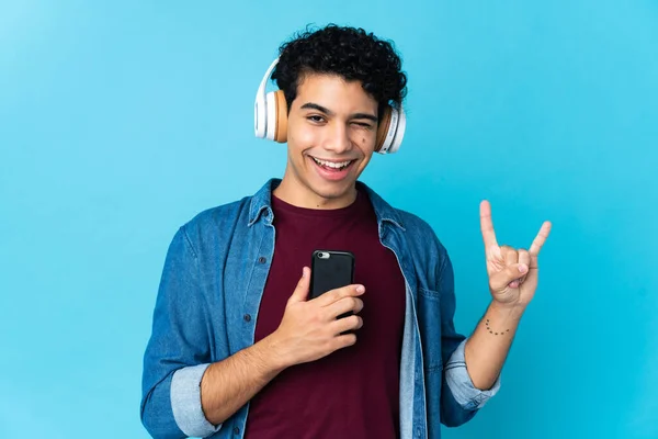 Νεαρός Βενεζουέλας Απομονωμένος Μπλε Φόντο Ακούγοντας Μουσική Μια Κινητή Ροκ — Φωτογραφία Αρχείου