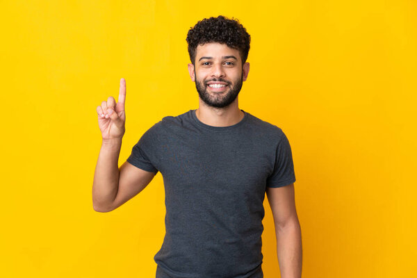 Young Moroccan man isolated on yellow background pointing up a great idea