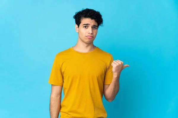 Young Venezuelan Man Isolated Blue Background Unhappy Pointing Side — Stock Photo, Image