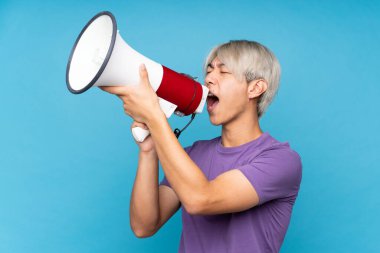 Soyutlanmış mavi arka planda genç Asyalı bir adam megafondan bağırıyor.