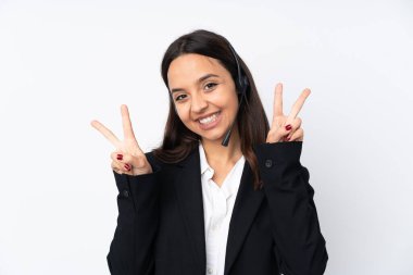 Beyaz arka planda izole edilmiş genç pazarlamacı kadın iki eliyle zafer işareti gösteriyor.