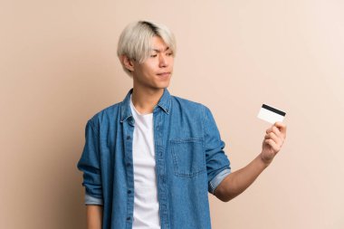Soyutlanmış geçmişi olan genç bir Asyalı kredi kartı tutuyor.