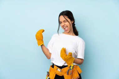 Genç elektrikçi kadın mavi arka planda izole edilmiş gitar hareketi yapıyor.