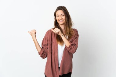 Beyaz arka planda izole edilmiş genç İrlandalı kadın bir ürün sunmak için kenarı işaret ediyor