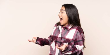 Genç Hintli kadın bej arka planda izole edilmiş.