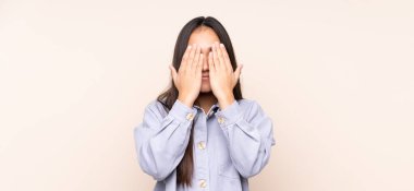 Genç Hintli kadın bej arka planda izole edilmiş gözleri elleriyle kaplayan