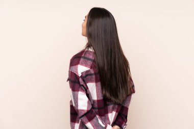 Genç Hintli kadın bej arka planda izole edilmiş ve arkasına bakıyor.