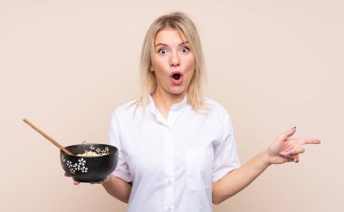 Tecrit edilmiş bir geçmişi olan genç bir Rus kadın elinde çubuklarla bir kase erişte tutarken şaşırmış ve onu işaret ediyordu.