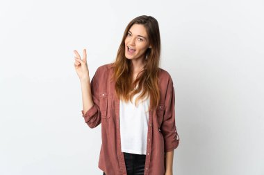 Beyaz arka planda izole edilmiş genç İrlandalı kadın gülümsüyor ve zafer işareti gösteriyor.