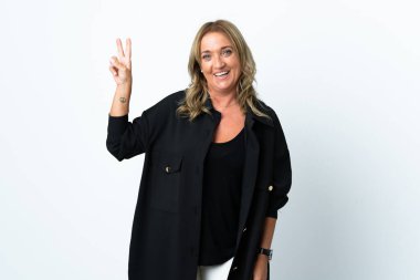 Orta yaşlı sarışın kadın izole edilmiş beyaz arka planda gülümsüyor ve zafer işareti gösteriyor.