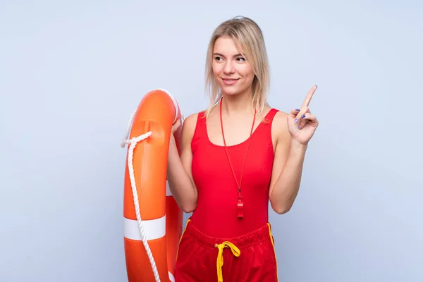 Lifeguard woman over isolated blue background with lifeguard equipment and intending to realizes the solution