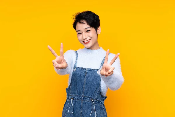 Menina Asiática Macacão Sobre Isolado Fundo Amarelo Sorrindo Mostrando Sinal — Fotografia de Stock