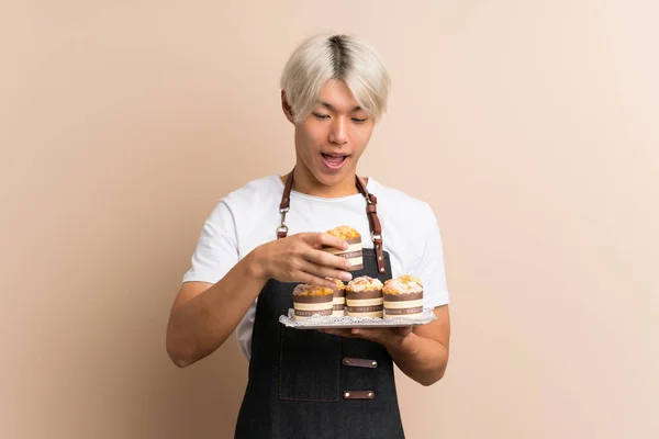 Joven Asiático Hombre Sobre Aislado Fondo Celebración Mini Pasteles Sorprendido — Foto de Stock