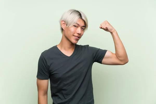 Mladý Asijský Muž Přes Izolované Zelené Pozadí Dělá Silné Gesto — Stock fotografie