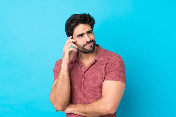 Joven Hombre Guapo Con Barba Sobre Fondo Azul Aislado Pensando —  Fotos de Stock