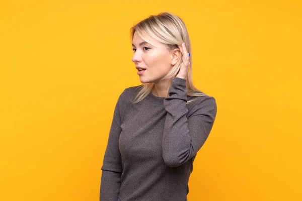 Young Blonde Woman Isolated Yellow Background Listening Something Putting Hand — Stock Photo, Image