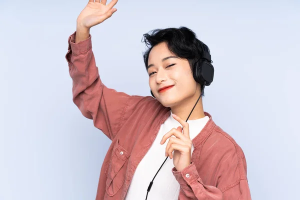 Joven Chica Asiática Sobre Fondo Azul Aislado Escuchando Música Bailando — Foto de Stock