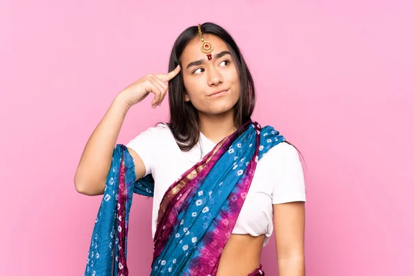 Young Indian woman with sari over isolated background making the gesture of madness putting finger on the head