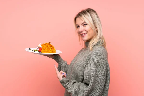 Jonge Blonde Vrouw Houden Wafels Geïsoleerde Roze Achtergrond Wijzen Het — Stockfoto