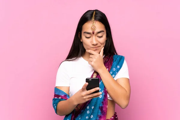 Young Indian woman with sari over isolated background thinking and sending a message