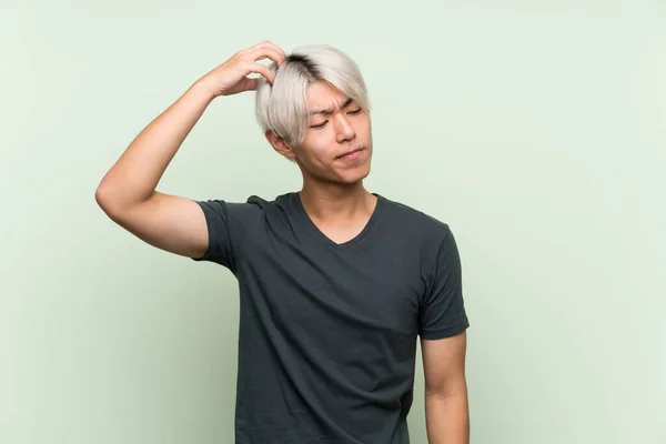Joven Asiático Hombre Sobre Aislado Verde Fondo Tener Dudas Mientras — Foto de Stock