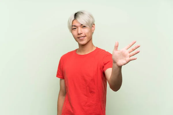 Mladý Asijský Muž Nad Izolované Zelené Pozadí Salutování Rukou Šťastným — Stock fotografie
