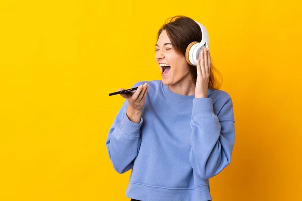 아일랜드의 여자가 휴대폰으로 음악을 노래를 부르면서 배경에 고립되어 — 스톡 사진